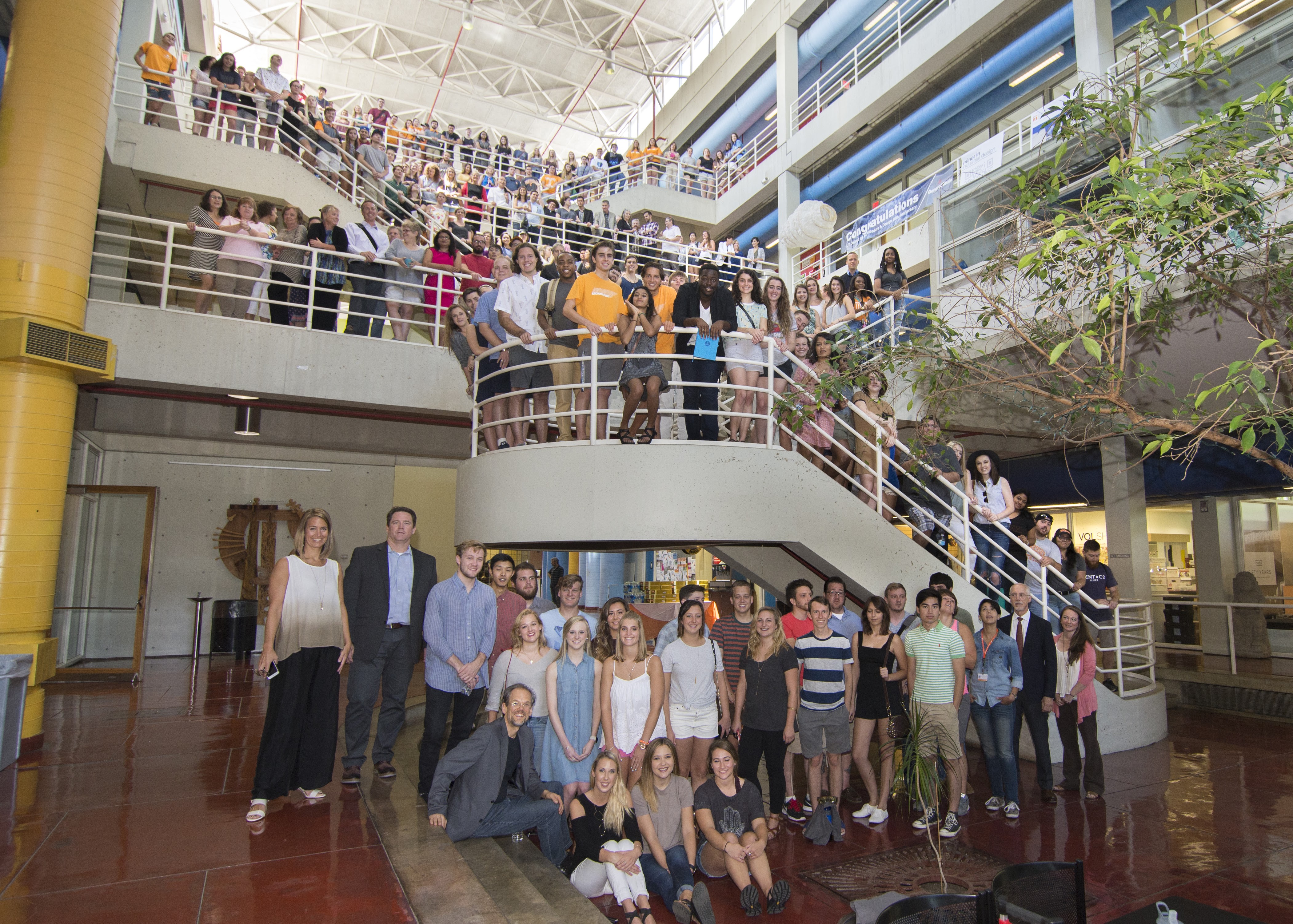 Students and faculty from the college gather on the stairs in the Art + Architecture Building.